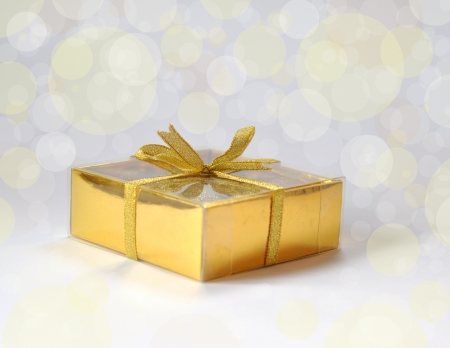 A gift in gold box with bow on gentle backgroundの写真素材