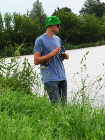 A young boy fishing from the shore in summer                             の写真素材