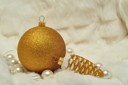 Christmas decorations in gold and white colors: cones and balls on a white fur closeupの写真素材