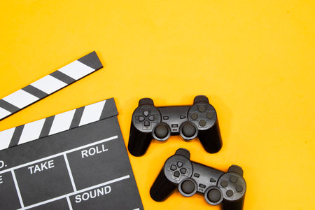 movie clapper and game console on yellow backgroundの写真素材