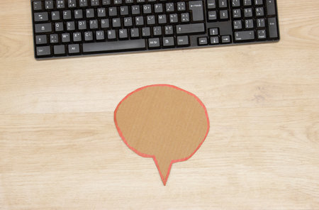 Computer keyboard and speech bubble onwooden table officeの写真素材