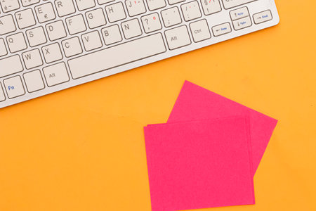 red sticky note and keyboard on orange backgroundの写真素材