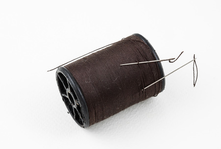spool of thread with needle on white background