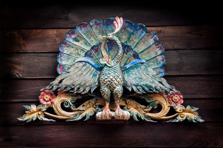 Old carving of peacock with beautiful color on wooden pedimentの写真素材