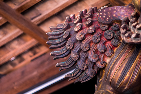 Chinese carving wooden lion decorated by stick to pillar,close up at tailの写真素材