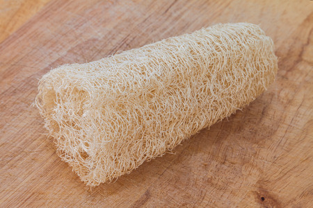 Used loofah on ligh brown wooden board backgroundの写真素材