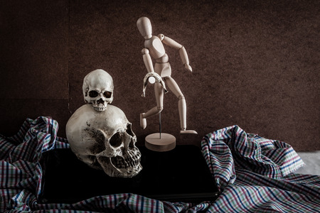 skull,wooden figure, old vintage camera and notebook on fabric.vintage colorの写真素材