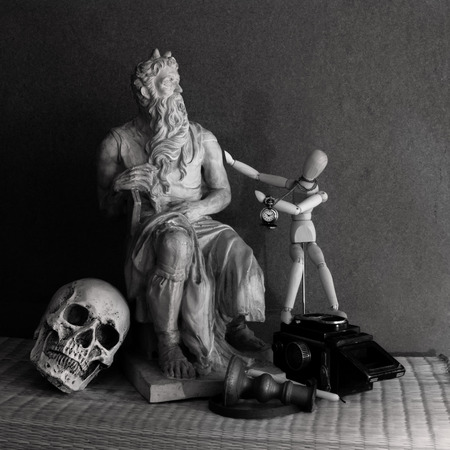 Still life of moses statue ,skull,wooden figure on mat with wooden backgroundの写真素材
