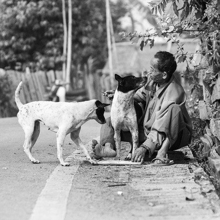 LAMPANG, THAILAND - 26 FEB : Unknow villager play and kiss his dog while he working at side of street, way of life of people in upcontry,Thailand on 26 Feb 2012のeditorial素材