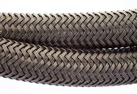 Close up of black woven braided tube housing cable on white
