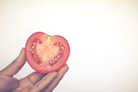 Half cut of red potato looking like heart shape in human hand on white backgroundの写真素材