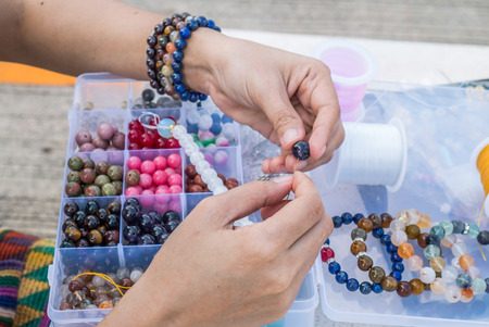 Close up of girl's hand threading beads on drawstring to make artistic bead necklace or braceletの写真素材