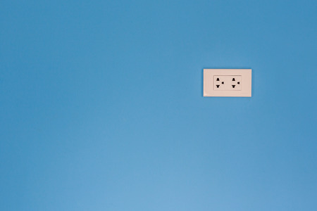 White electric outlet mounted on pink cement wall with doodle  painting