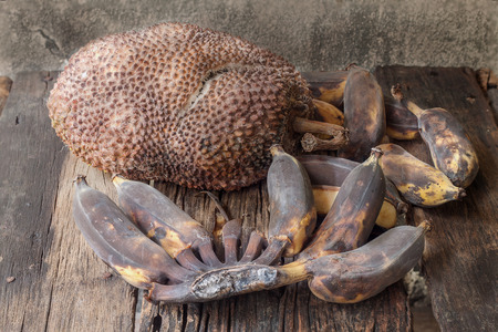 Rotten jackfruit and banana on wooden floor and old cement wallの写真素材