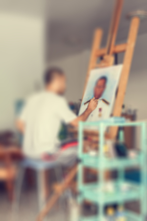 Blur of artist painting a man portrait on easel in studioの写真素材