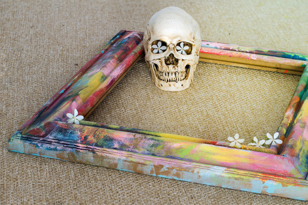 Tiny skulls with colorful wooden frame and Wrightia religiosa flowerの写真素材