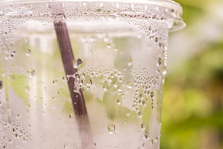 Water drop on plastic bottle of drink with green background backgroundの写真素材