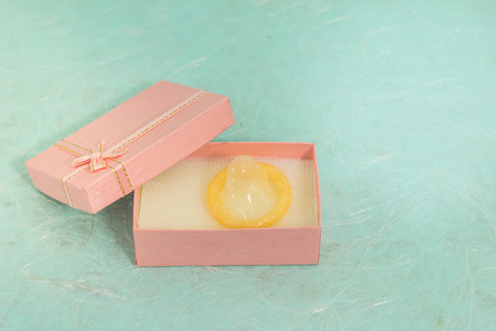 Yellow condom in small gift box on green mullberry paperの写真素材