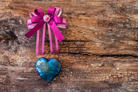 Purple ribbon and heart shape Labradorite gemstone on old rough brown wooden boardの写真素材