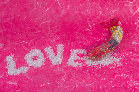 Love wording arrange by bead with thread bead in condom on pink mulberry paper background