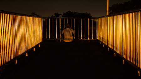 Unidentified man sitting on footbridge in Bangkok,Thailand at twilight timeの写真素材