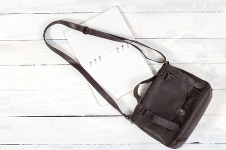 Leather bag with notebook on white wooden backgroundの写真素材
