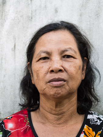 Close up old Thai woman portrait with cement wall backgroundの写真素材