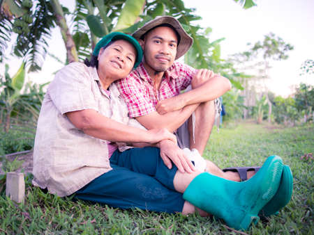 Asian agriculturist, mother and son, sitting on yard in their garden, Thailandの写真素材