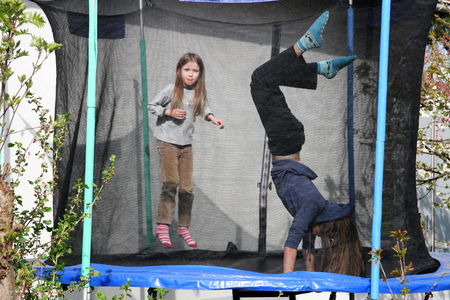 Two blonde girls jumping on the trampolineの写真素材