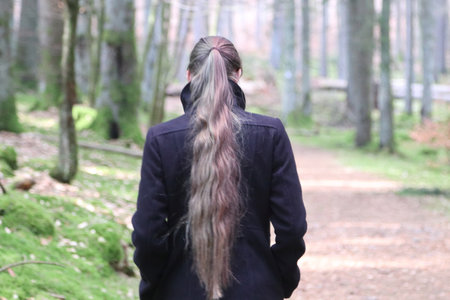Young woman with long hair walking through the forestの写真素材