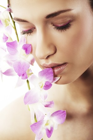 Beautiful young woman with orchid flowersの写真素材