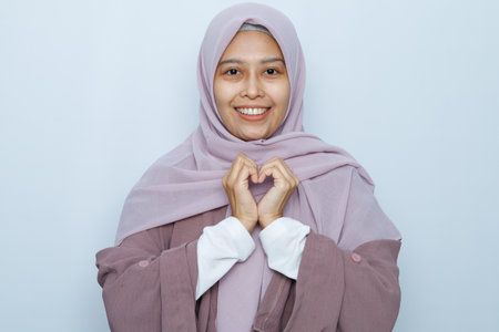 A radiant Asian woman, exudes joy against a white backdrop, her beauty and cheerful spirit captivating in a stunning portraitの写真素材