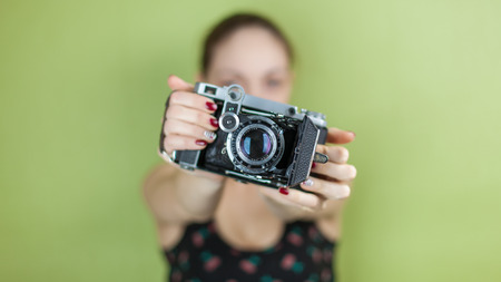 smiling girl with vintage  retro camera taking photo on green backgroundの写真素材