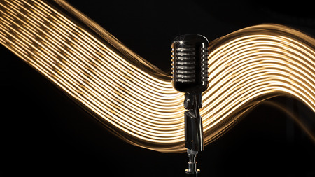 Vintage retro microphone on the black background with light waveの写真素材