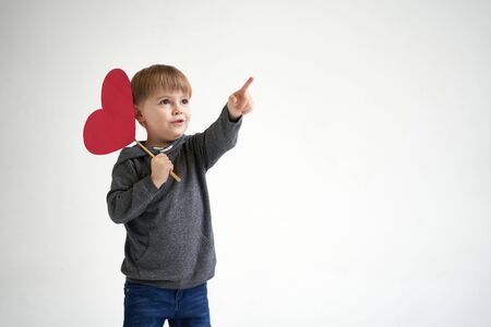 Sweet boy holding red paper heart on white background. Valentines day or kids healthcare, medical conceptの写真素材