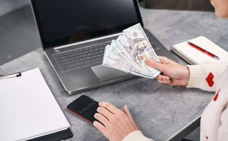 Woman hands counting cash money using calculator on her smartphoneの写真素材