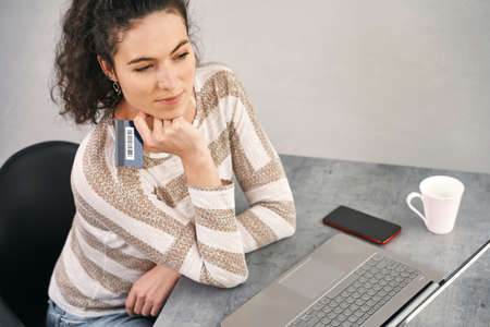 Happy woman holding credit card and using laptop for buying onlineの写真素材