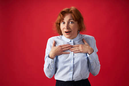 Beautiful redhead woman surprised on red background