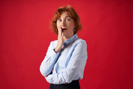 Beautiful redhead woman surprised on red backgroundの写真素材