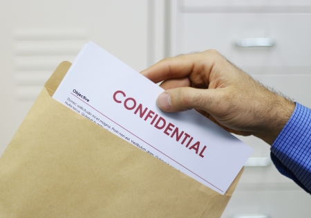 Cropped view image of a man handling confidential documents placing them inside a brown manilla envelope for mailingの写真素材