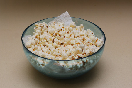 Homemade popcorn in a glass bowl on an oil obsreving tissue paperの写真素材