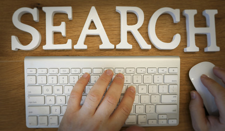 Top view on hands typing on wireless keyboards with 3d wooden cut letters on topの写真素材