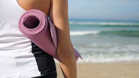 Young attractive woman holding sport equipment for yoga and training on outdoorの写真素材