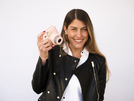 Young attractive woman holding instant semi toy camera and smiling to the cameraの写真素材