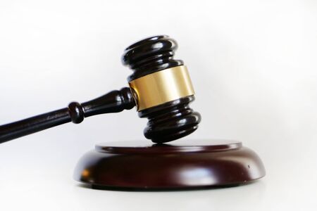 Court gavel used by judge lay on white surface side viewの写真素材