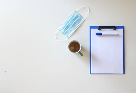 Desktop with writing tools and surgical mask during coronavirus pandemicの写真素材