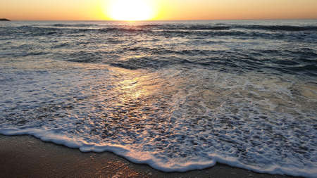 Sunset landscape with vivid colors and sea level waves on the shore