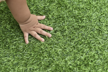 photo of baby hand touching the green grass to feel the texture.concept of learning to growの写真素材