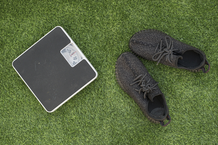 photo of weighing scale with running shoes on a green grass.concept of weight loss and health fitnessの写真素材
