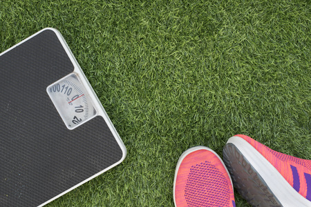 photo of weighing scale with running shoes on a green grass.concept of weight loss and health fitnessの写真素材